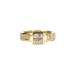 Crafted in 14KT gold, this engagement ring features a raised bezel set princess cut diamond. Band is set with princess-cut diamonds.