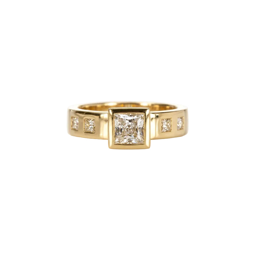 Crafted in 14KT gold, this engagement ring features a raised bezel set princess cut diamond. Band is set with princess-cut diamonds.