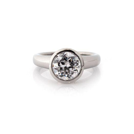 Crafted in 14KT white gold, this ring features a bezel set round-cut diamond with signature trademark on both sides. 