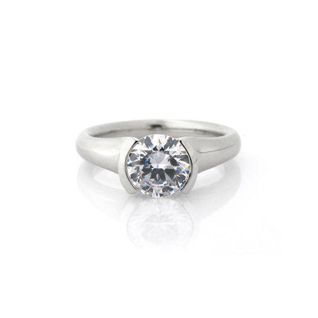Crafted in 14KT white gold, this ring features a half-bezel set round brilliant-cut diamond with signature trademark on both sides. 