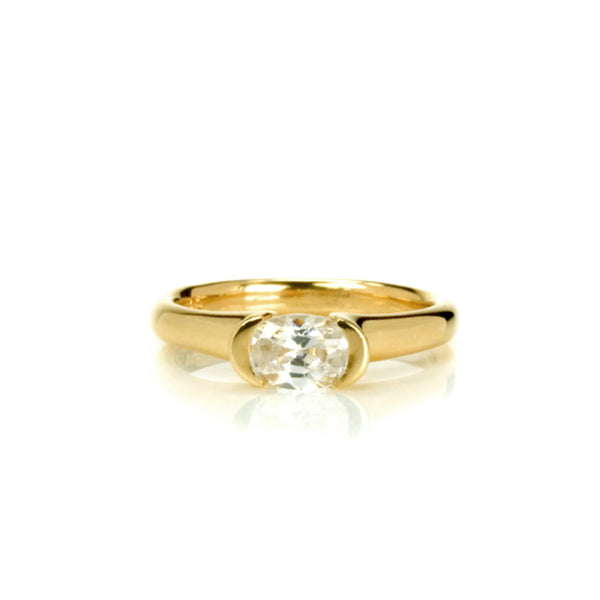 Crafted in 14KT yellow gold, this ring features an oval-cut diamond in a half-bezel setting.